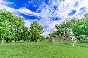 A soccer goal is in the middle of a grassy field.