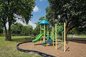 A playground with a green slide and a blue canopy.