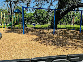 A playground with a blue swing set and a green slide.