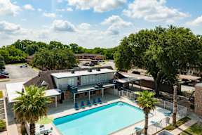 A pool surrounded by trees and a building in the background.