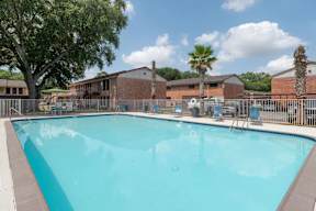 A large swimming pool surrounded by a fence and trees.