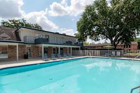 A large swimming pool in front of a building with a tree in the background.