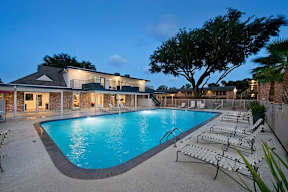 A swimming pool in front of a house with lounge chairs around it.