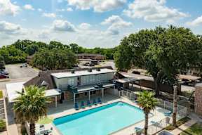 A pool surrounded by trees and a building in the background.
