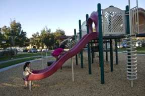 a girl playing on a slide on a playground