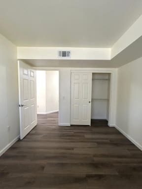 a living room with white walls and wooden floors and a closet
