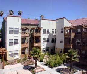a row of apartment buildings with palm trees in the courtyard