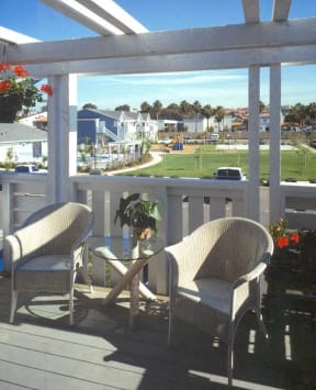 a deck with two chairs and a table and a view of a body of water