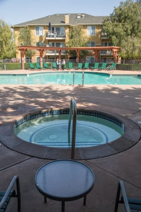 a large swimming pool with a table and chairs in front of a building