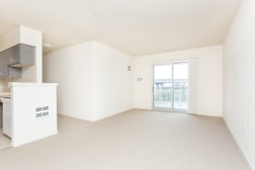 an empty living room and kitchen with a door to a balcony