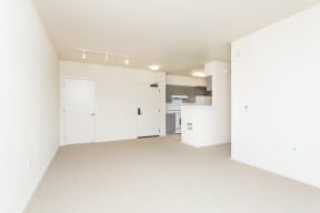 an empty living room and kitchen with white walls and carpet