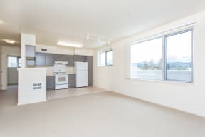 an empty room with a kitchen and a large window