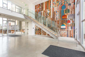 the lobby of a building with a staircase and art on the wall