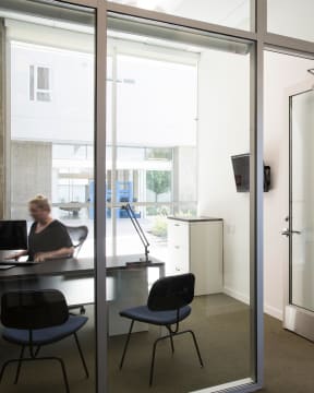 a woman working at a desk in an office with glass doors