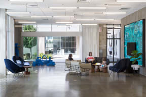 a large lobby with furniture and a woman sitting in a chair