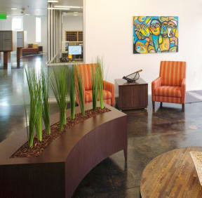 a reception area with orange chairs and a table with plants