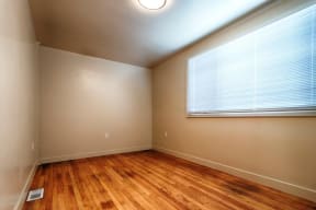 an empty room with a large window and wood floors