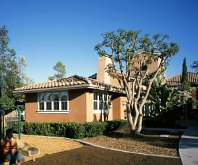 a man sitting in front of a house with a tree