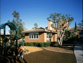 a child playing on a playground in front of a house