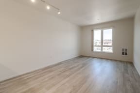 an empty living room with wood floors and a window