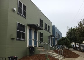 the exterior of a green building with stairs and blue doors