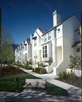 a row of white houses with a park bench