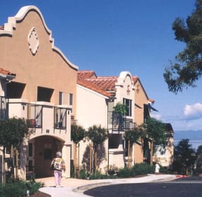 a woman walking down the sidewalk outside of a building