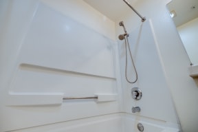 a shower in a bathroom with white walls and a silver shower head