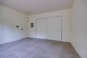 a bedroom with white walls and carpet and two closets