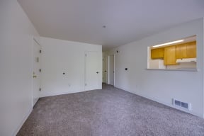 the living room of an apartment with white walls and carpet