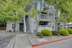 front view of a gray house with stairs and trees
