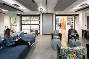 a common area with people sitting on couches and chairs and a man and woman