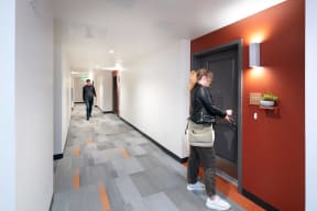 a woman is standing in front of a door in a hallway
