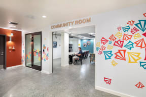 a person sitting at a table in a room with a community room sign
