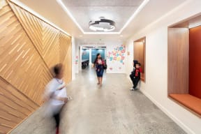 people walking down a hallway in a building with wooden walls