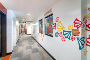 a hallway with a colorful mural on the wall and a person walking down the hall