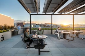a group of people sitting at tables on a rooftop patio