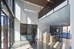 a large lobby with a reception desk and people walking