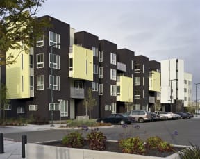 a rendering of a modern apartment building with black and yellow facade and a parking lot