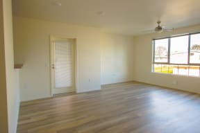 an empty living room with wood floors and a window
