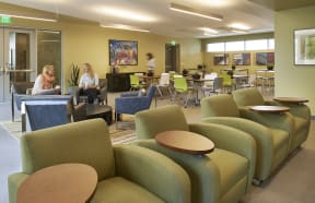a lounge area with chairs and tables and people sitting at tables