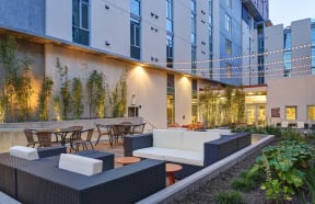 a patio with a couch and tables in front of a building
