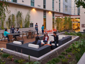 a group of people sitting on couches in a garden outside a building