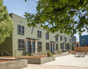 a row of green buildings with trees in front of them