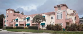 a row of pink and white apartments on the side of a street