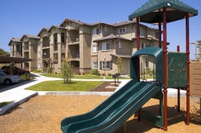 a playground with a slide in front of an apartment building