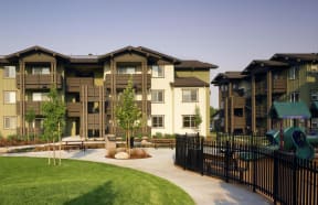 an apartment building with a playground and green grass