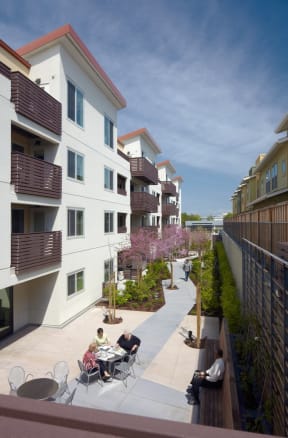 people sitting at tables on a patio outside of apartments