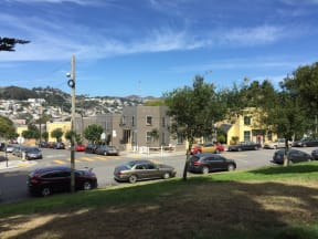 a view of a city street with cars parked on the grass