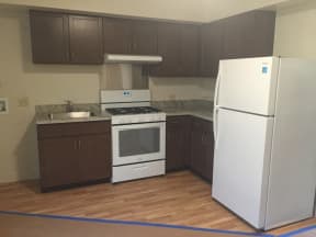 an empty kitchen with white appliances and brown cabinets